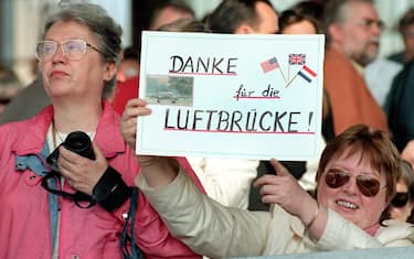 BER01 - 19980514 - BERLIN, GERMANY : Visitors of the ceremony marking the 50th anniversary of the Berlin airlift that supplied the  western part of the divided city as it was blockaded by Soviet forces in 1948-49, hold a self-styled placard reading "Thanks for the airlift" as they wait for US President Bill Clinton to arrive at Berlin-Tempelhof airport 14 May.    EPA/DPA/BERND SETTNIK 