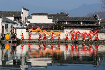 HUANGSHAN, CHINA - FEBRUARY 10: Members of a dragon dance team take part in a parade to celebrate the Chinese Lunar New Year on February 10, 2024 in Hongcun Village, Huangshan City, Anhui Province of China. The Spring Festival, or the Chinese Lunar New Year, falls on February 10 this year. (Photo by Shi Yalei/VCG via Getty Images)