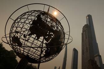 NEW YORK, NY - JUNE 7:  Smoke shrouds the sun as it rises behind a sculpture of the earth in Columbus Circle and Central Park Tower on June 7, 2023, in New York City.  (Photo by Gary Hershorn/Getty Images)