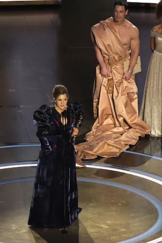 HOLLYWOOD, CALIFORNIA - MARCH 10: Holly Waddington accepts the Best Costume Design award for "Poor Things" from John Cena onstage during the 96th Annual Academy Awards at Dolby Theatre on March 10, 2024 in Hollywood, California. (Photo by Kevin Winter/Getty Images)