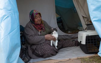 KAHRAMANMARAS, TURKIYE - FEBRUARY 24: Medine Bunsuz, an earthquake survivor lives the tent city established in Vali Saim Cotur Stadium and around with her cat named "Mino" after 7.7 and 7.6 magnitude earthquakes hit multiple provinces of Turkiye including Kahramanmaras on February 24, 2023. Some survivors of earthquakes in Kahramanmaras live together in a tent city with their animals, such as fish, birds, partridges, cats and dogs, which they rescued while leaving their homes. Established by the Sakarya 7th Commando Brigade Command, the tent city hosts nearly 3,500 earthquake victims as well as dozens of pets. (Photo by Fatih Kurt/Anadolu Agency via Getty Images)
