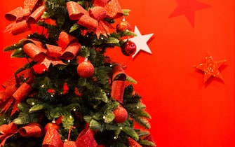 Christmas tree decorated with red baubles & ribbons, UK.