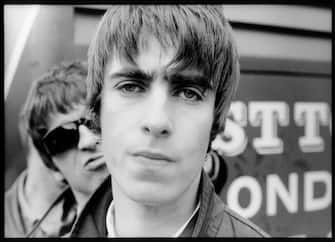 NETHERLANDS - JANUARY 01:  NETHERLANDS  Photo of Liam GALLAGHER and OASIS and Noel GALLAGHER, Liam Gallagher with Noel Gallagher behind (sneering, wearing sunglasses) - posed  (Photo by Michel Linssen/Redferns)