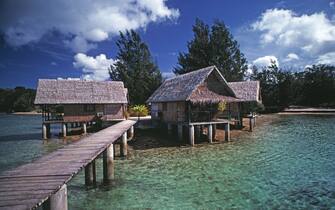 Vanuatu. Efate. Port Vila. Overwater thatched bungalow huts on waterfront.