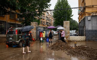 epa10779145 People walk near debris during a downpour in Mentougou District, west of Beijing, China, 01 August 2023. Heavy rains brought by Typhoon Doksuri caused floods in northern China and left two dead and thousands being evacuated as Beijing experienced its heaviest rainfall of the year.  EPA/MARK R. CRISTINO