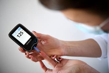 A woman with diabetes uses a glucometer to measure the glycemia in her blood in Paris on March 24, 2020, on the eighth day of a strict lockdown in France aimed at curbing the spread of COVID-19 caused by the novel coronavirus. (Photo by FRANCK FIFE / AFP) (Photo by FRANCK FIFE/AFP via Getty Images)