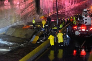Rescuers search for people trapped under a wall that collapsed on several vehicles after heavy rains on 27 de Febrero Avenue in Santo Domingo on November 18, 2023. (Photo by Felix Leon / AFP) (Photo by FELIX LEON/AFP via Getty Images)