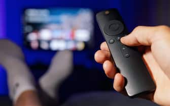 hand with tv remote control. man watching streaming service content at home