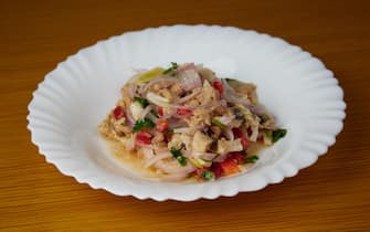 Peruvian hake and tune ceviche with vegetables, spices and lime on a white plate