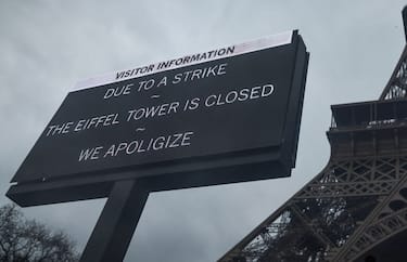 This photograph taken on February 19, 2024, in Paris, shows a board informing visitors that the Eiffel Tower, viewed in the background (R), is closed as staff go on strike, over the financial management of the monument by the city, closing the monument to the public during the second week of the French school holidays. Unions of the operating company of the Eiffel Tower, the CGT and Force Ouvriere say the city, which owns 99 percent of the tower, has underestimated costs and overestimated revenues, whilst also hinting to the threat of a strike during the Olympic Games, held in Paris from July 26 to August 11. (Photo by Kiran Ridley / AFP) (Photo by KIRAN RIDLEYKIRAN RIDLEY/AFP via Getty Images)