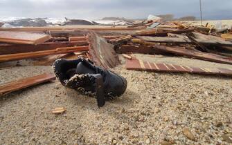 A shoe is seen amid the remains of the boat after migrants washed ashore following a shipwreck, at a beach near Cutro, Crotone province, southern Italy, 26 February 2023. Italian authorities recovered at least 40 bodies on the beach and in the sea near Crotone, in the southern Italian region of Calabria, after a boat carrying migrants sank in rough seas near the coast. About forty people survived the accident, Authorities fear the death toll will climb as rescuers look for survivors. ANSA/ GIUSEPPE PIPITA