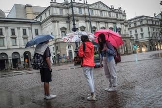 Persone si riparano con gli ombrelli dalla pioggia nel centro di Milano, 18 agosto 2022. ANSA/MATTEO CORNER