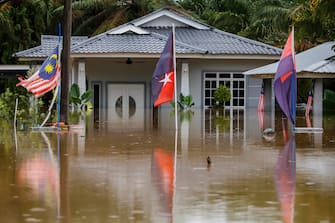 epaselect epa10501877 Malaysian and Johor flags flutter in front of a flooded house in Yong Peng, Johor, Malaysia, 04 March 2023. According to state media, more than 33,000 people were evacuated in four states affected by the floods.  EPA/FAZRY ISMAIL