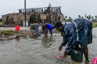 epa10521046 Women wash some clothes in a stream after the destruction caused by the storm Freddy in Quelimane, Mozambique, 13 March 2023. This is one of the longest lasting storms ever, after it formed at the beginning of February in the Asian seas, crossing the entire Indian Ocean to the east African coast.  EPA/ANDRÉ CATUEIRA