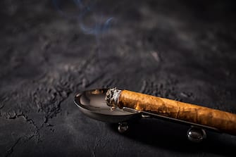 Premium cigar placed in ashtray on black background