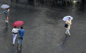 Passanti con ombrelli durante il temporale che si e' abbattuto su Roma, 13 giugno 2023 .  ANSA/ETTORE FERRARI  (turisti, ombrello, ombrelli, pioggia)