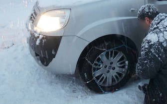 Neve in tutta Italia, ondata di gelo su tutto il Paese. In foto Persone che si montano le catene da neve sull'auto nel centro di Firenze