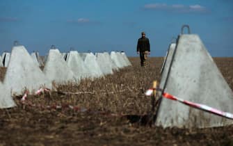 epa11215096 A man walks among concrete protections as workers build a fortification line at an undisclosed location in the Zaporizhzhia region, Ukraine, 11 March 2024, amid the Russian invasion. Ukraine began to build huge defense lines protecting 2,000 kilometers near the frontline, as confirmed by Ukrainian President Volodymyr Zelensky following a High Command General Headquarters sitting on 11 March.  EPA/KATERYNA KLOCHKO