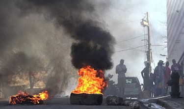 TOPSHOT - This screen grab taken from AFPTV shows tires on fire near the main prison of Port-au-Prince, Haiti, on March 3, 2024, after a breakout by several thousand inmates. At least a dozen people died as gang members attacked the main prison in Haiti's capital, triggering a breakout by several thousand inmates, an AFP reporter and an NGO said on March 3. "We counted many prisoners' bodies," said Pierre Esperance of the National Network for Defense of Human Rights, adding that only around 100 of the National Penitentiary's estimated 3,800 inmates were still inside the facility after the gang assault overnight on March 2. (Photo by Luckenson JEAN / AFPTV / AFP) (Photo by LUCKENSON JEAN/AFPTV/AFP via Getty Images)