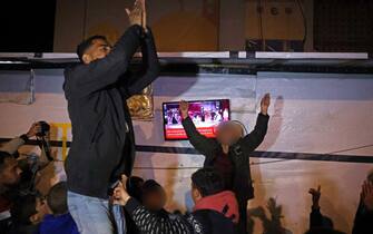 Persone festeggiano in strada a Gaza per l'accordo fra Israele e Hamas People celebrate while watching a television along a street in Khan Yunis in the southern Gaza Strip on January 15, 2025, amid the ongoing war in the Palestinian territory between Israel and Hamas. Thousands of Gazans celebrated on January 15 as news spread that a ceasefire and hostage release deal had been reached between Israel and Hamas, aimed at ending more than 15 months of war in the Palestinian territory. (Photo by BASHAR TALEB / AFP)