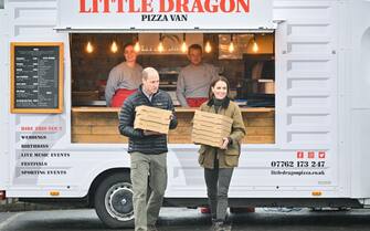 MERTHYR TYDFIL, WALES - APRIL 27: Prince William, Prince of Wales and Catherine, Princess of Wales smile while carrying pizza boxes at Dowlais Rugby Club during a 2 day visit to Wales on April 27, 2023 in Merthyr Tydfil, Wales. The Prince and Princess of Wales are visiting the country to celebrate the 60th anniversary of Central Beacons Mountain Rescue and to meet members of local communities. (Photo by Samir Hussein/WireImage)