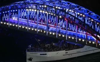 TOPSHOT - A boat with the France's delegation passes under the passerelle Debilly footbridge where a show is going on it sails on the river Seine during the opening ceremony of the Paris 2024 Olympic Games in Paris on July 26, 2024. (Photo by Luis ROBAYO / POOL / AFP)