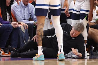 PHOENIX, ARIZONA - APRIL 28: Head coach Chris Finch of the Minnesota Timberwolves grabs in leg in pain after a collision with Mike Conley (not pictured) during the second half of game four of the Western Conference First Round Playoffs against the Phoenix Suns at Footprint Center on April 28, 2024 in Phoenix, Arizona. The Timberwolves defeated the Suns 122-116 and win the series 4-0. NOTE TO USER: User expressly acknowledges and agrees that, by downloading and or using this photograph, User is consenting to the terms and conditions of the Getty Images License Agreement.  (Photo by Christian Petersen/Getty Images)