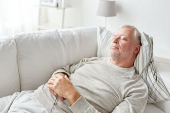 senior man sleeping on sofa at home