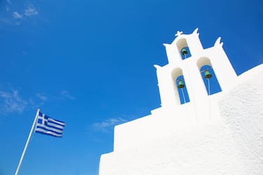 Greece, Cyclades islands Naxos village, may 28/2019.  a bell tower and national flag of greece  Greek Orthodox chapel.