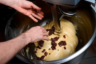 A pastry chef adds raisins in the dough during the making of a traditional Christmas sweetbread "Panettone" on December 6, 2017 at the Pasticceria San Gregorio in Milan. The Panettone, a typical brioche of the Lombardy region, is traditionally stuffed with raisins, candied fruits and citrus zest.  / AFP PHOTO / MIGUEL MEDINA / AFP PHOTO / MIGUEL MEDINA        (Photo credit should read MIGUEL MEDINA/AFP via Getty Images)