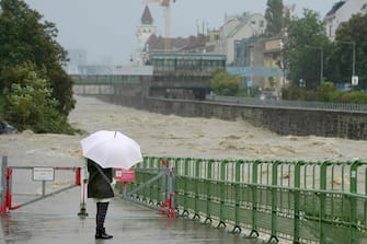 TOPSHOT - A pedestrian looks at the high level of the Wien river in Hutteldorf, Vienna, during heavy rainfall on September 15, 2024. Four people have died in Romania in floods triggered by Storm Boris, which has brought torrential rains and widespread disruption to central and eastern Europe, rescue services said on September 14, 2024.  Since September 12, swathes of Austria, the Czech Republic, Hungary, Romania and Slovakia have been hit by high winds and unusually fierce rains. (Photo by GEORG HOCHMUTH / APA / AFP) / Austria OUT