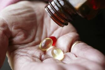 Elderly woman pouring vitamin pills on hand (Photo by Universal Images Group via Getty Images)