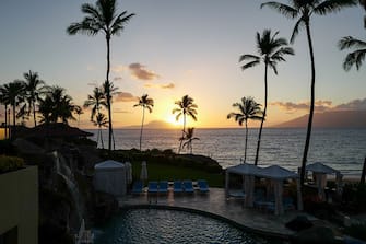 Sunset at Wailea Beach, as viewed from the Four Seasons Resort Maui at Wailea, palm trees and pool visible, Wailea, Maui, Hawaii, 2016. (Photo by Smith Collection/Gado/Getty Images).