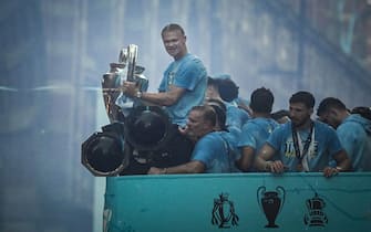 TOPSHOT - Manchester City's Norwegian striker Erling Haaland holds the European Cup as he celebrates with teammates their three trophies including the FA Cup and the Premier League ones during an open-top bus victory parade in the streets of Manchester, northern England on June 12, 2023. Manchester City tasted Champions League glory at last on Saturday as a second-half Rodri strike gave the favourites a 1-0 victory over Inter Milan in a tense final, allowing Pep Guardiola's side to complete a remarkable treble. Having already claimed a fifth Premier League title in six seasons, and added the FA Cup, City are the first English club to win such a treble since Manchester United in 1999. (Photo by Paul ELLIS / AFP) (Photo by PAUL ELLIS/AFP via Getty Images)