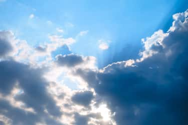 Sun rays over the low rain clouds. Stormy dramatic sky background.