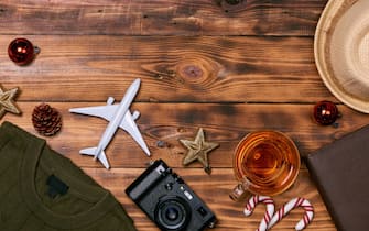 Preparation for travel concept - Toy plane, camera, cup of tea, xmas decorations  on wooden background.