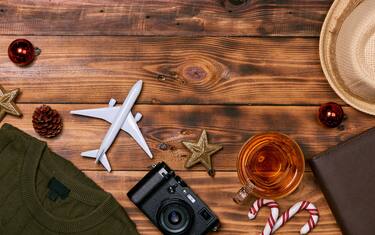 Preparation for travel concept - Toy plane, camera, cup of tea, xmas decorations  on wooden background.