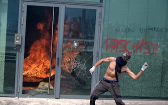 A protester clashes with police, next to a tag reading 'Neither forgetting nor forgiving' (R), during a commemoration march for a teenage driver shot dead by a policeman, in the Parisian suburb of Nanterre, on June 29, 2023. Violent protests broke out in France in the early hours of June 29, 2023, as anger grows over the police killing of a teenager, with security forces arresting 150 people in the chaos that saw balaclava-clad protesters burning cars and setting off fireworks. Nahel M., 17, was shot in the chest at point-blank range in Nanterre in the morning of June 27, 2023, in an incident that has reignited debate in France about police tactics long criticised by rights groups over the treatment of people in low-income suburbs, particularly ethnic minorities. (Photo by Alain JOCARD / AFP)