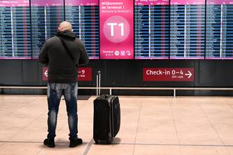 epa10519577 A passenger stands in front of electronic boards showing canceled flights at the Berlin-Brandenburg airport, Germany, 13 March 2023. The employees of aviation security and ground handling services called for a 24 hours strike over wages.  EPA/FILIP SINGER