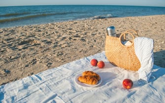 Summer picnic on the beach by the sea at a sunrise.