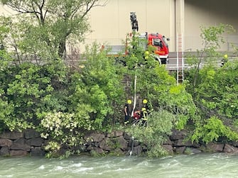 I vigili del fuoco posano dei tubi nell'Isarco per pompare l'acqua dal vicino fiume in modo da spegnere il rogo dell'Alpitronic, Bolzano, 8 maggio 2024. ANSA/GNEWS