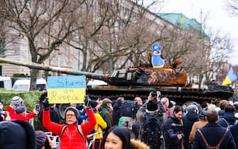 24 February 2023, Berlin: A man displays a sign reading "Shame on Russia" next to passers-by in front of a Russian tank destroyed in Ukraine. The T-72 tank is on a trailer in front of the Embassy of Russia on the street Unter den Linden in Berlin. This action is to be a sign of protest against Russia's war and is to express solidarity with Ukraine. The Russian army had invaded Ukraine on 24.02.2022. Photo: Carsten Koall/dpa (Photo by Carsten Koall/picture alliance via Getty Images)