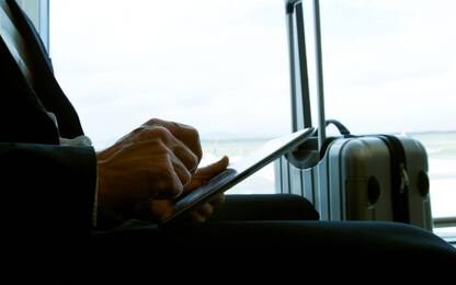 Businessman Traveler In Front Of Tablet Computer Young Tourist Sitting At Airport Holding His Bag Waiting For Flight, Holiday