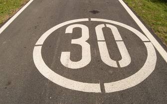 speed limit sign of 30 painted on rural road