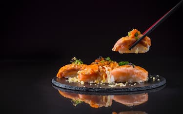 Salmon Nigiri, Burned Salmon Sushi and topped with Shrimp Eggs and Tempura with chopstick, Japanese food on ceramic dish, Japanese food style, Japanese Food menu, selective focus