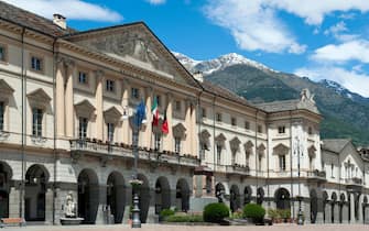 Town hall of Aosta in Italy. With text in French and Italian: Hotel de Ville and Municipio.At the background mountains with snow