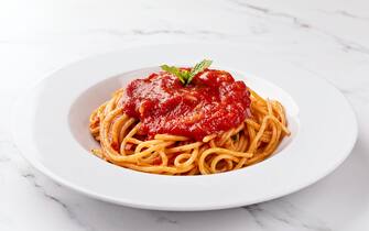 Front view of spaghetti with tomato sauce on white background.
