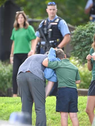 epa12327016 An adult and child comfort each other as they leave the school as police respond to a shooting at the Annunciation Catholic School in Minnesota, USA, 27 August 2025. According to police, three people including the gunman died in the shooting at a Catholic primary church and 20 were injured.  EPA/CRAIG LASSIG