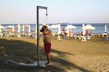 A man takes a shower after swimming on the beach in the evening in the Mediterranean port of Limassol. Cyprus, Monday, August 1, 2022. (Photo by Danil Shamkin/NurPhoto via Getty Images)