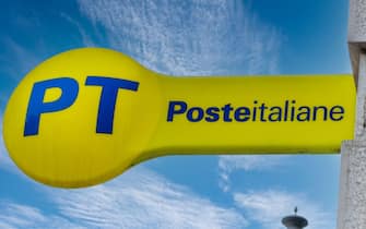 Cuneo, Italy - April 11, 2022: PT Poste Italiane, Italy Post logo on yellow sign on blue sky, outside the Italian post office. Tex: Posteitaliane (Ita